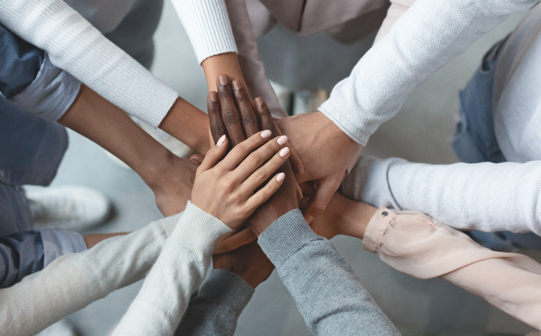 A team's hands are stacked in the center, representing collaboration and unity.