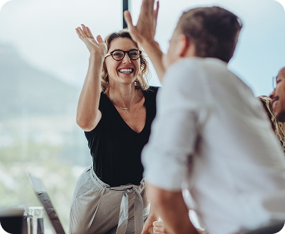 A team celebrates success with high-fives in an office setting.
