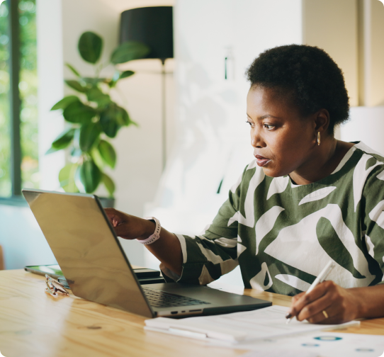 A female broker smiles while working on a laptop with a colleague.
