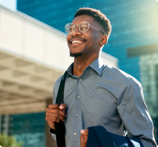 A male healthcare professional in a white coat smiles, carrying a bag.