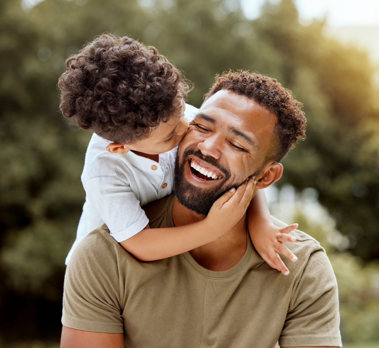A father and his child laugh together outdoors, symbolizing health and happiness.
