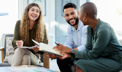 A team of colleagues collaborates on a laptop in a modern office setting, symbolizing teamwork.